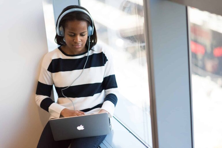 African woman browsing internet on the laptop with headphones. Concept for Tubidy