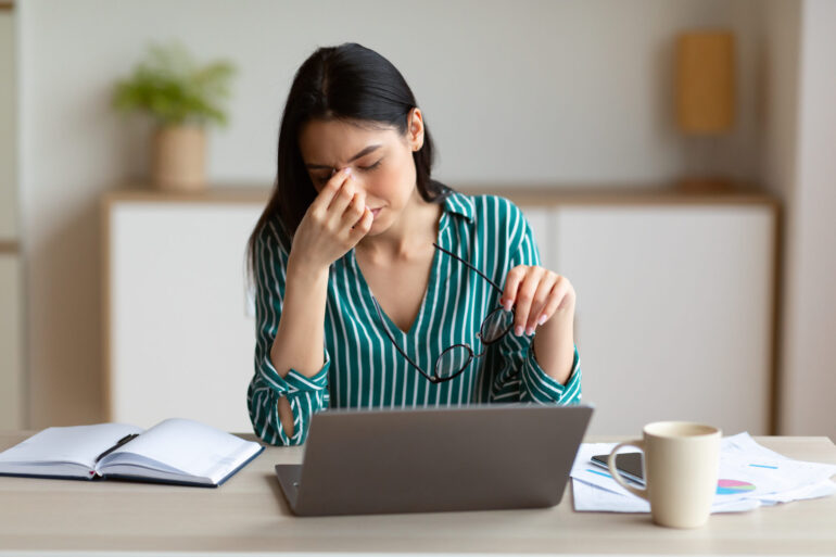 Woman Having Eyes Fatigue And Headache Massaging Nosebridge Working At Laptop Sitting In Modern Office