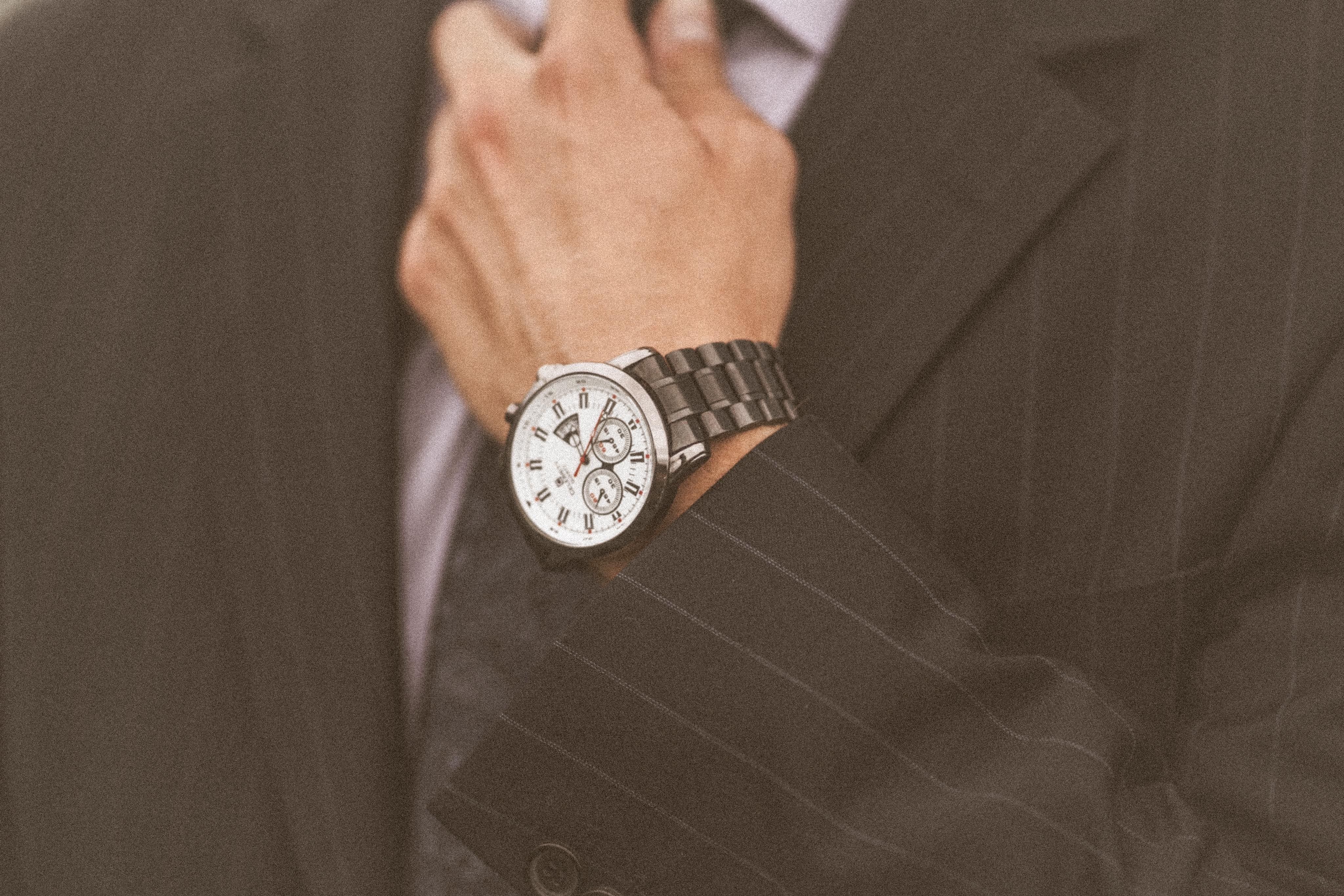 Close-up of a stylish man in a suit adjusting his tie and luxury wristwatch, embodying power and success
