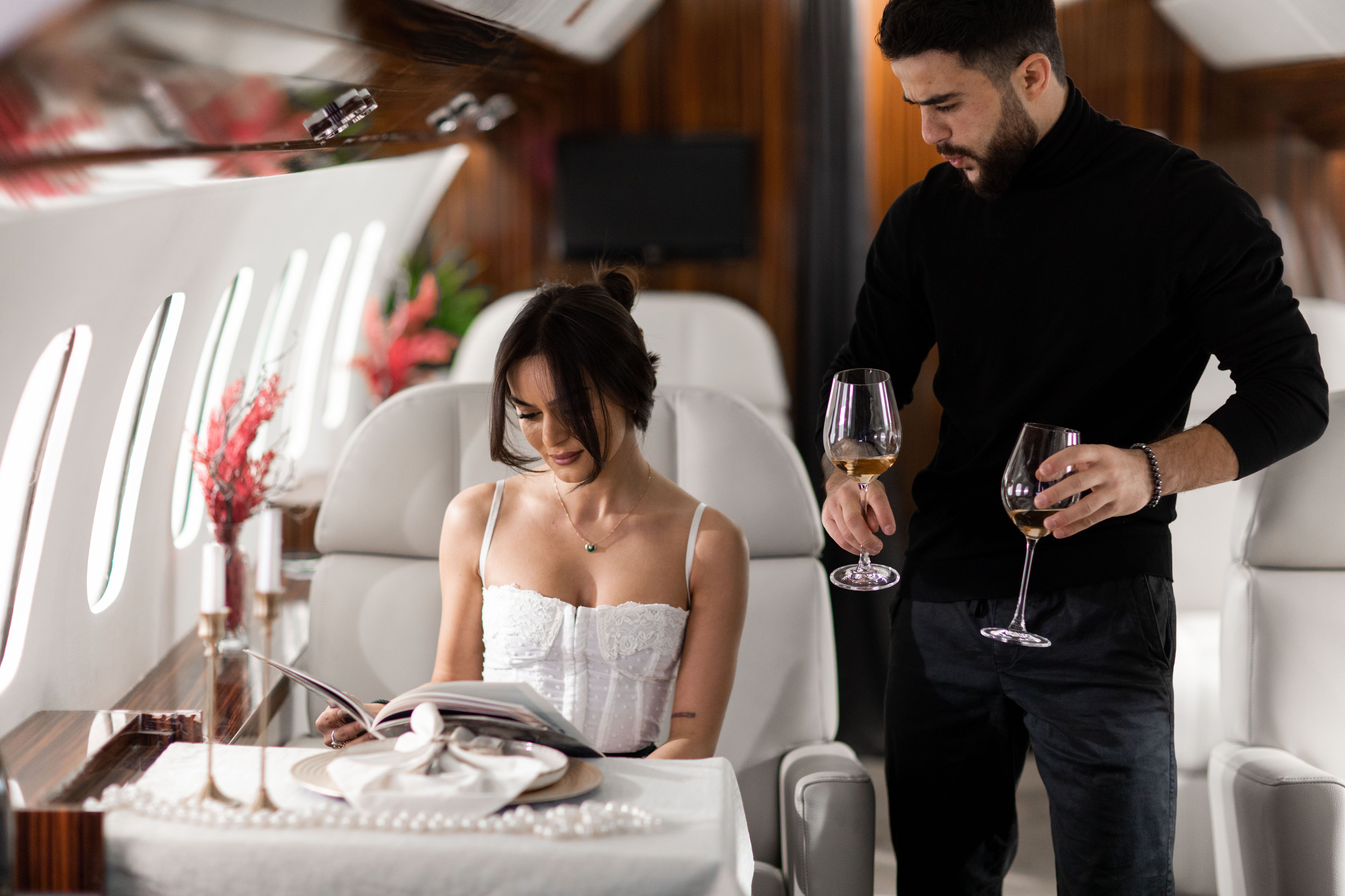 Elegant couple enjoying wine in a luxurious private jet interior representing a high-wealth sugar daddy lifestyle